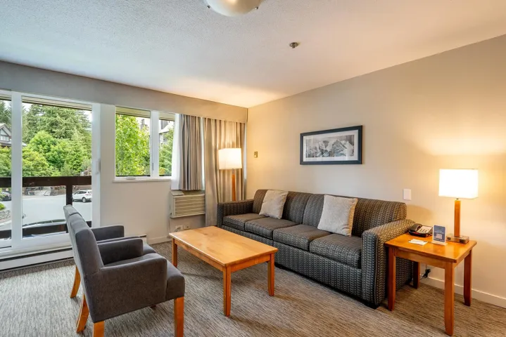 Carpeted living area with baseboards and a textured ceiling