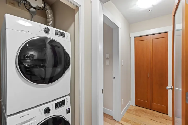 Laundry area with light wood-type flooring and stacked washer / drying machine