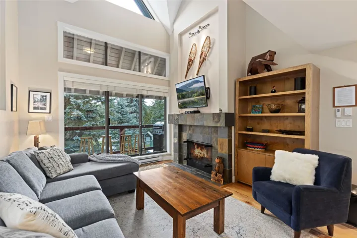 Living area featuring a high ceiling, wood finished floors, and a tiled fireplace