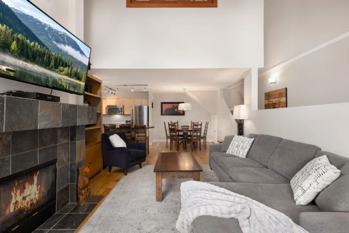 Living room with wood finished floors, a fireplace, and a high ceiling