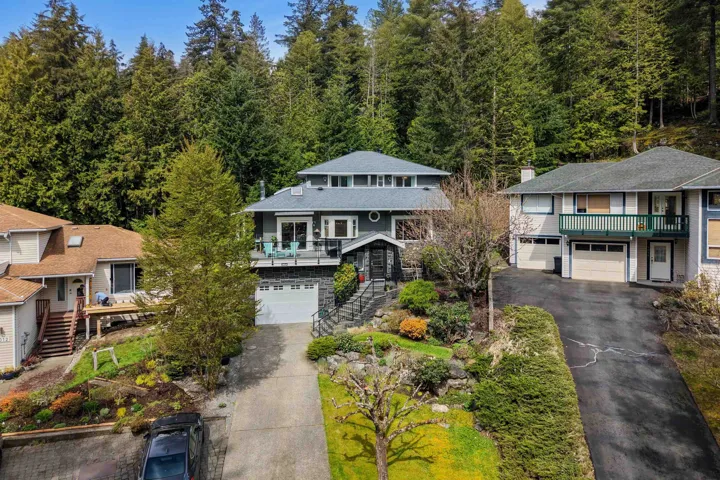View of front of house with driveway, a garage, a balcony, a chimney, and roof with shingles