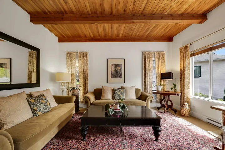 Living area with a wood ceiling with exposed beams and a baseboard heating unit