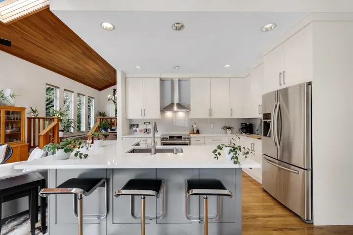 Kitchen featuring stainless steel appliances, a vaulted wood ceiling, white cabinetry, and a breakfast bar