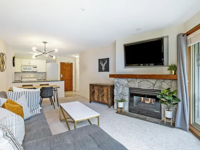 Living area featuring light carpet, a chandelier, and a stone fireplace