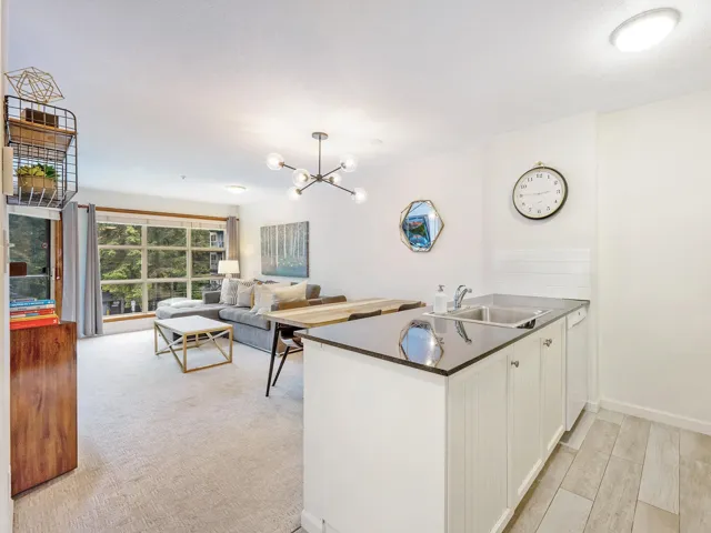 Kitchen with a peninsula, white cabinetry, dark countertops, a chandelier, and open floor plan