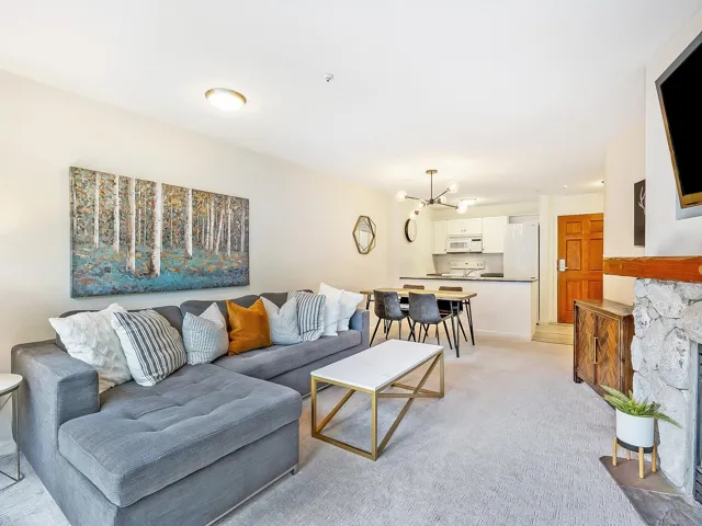 Living area with a chandelier, a stone fireplace, and light carpet