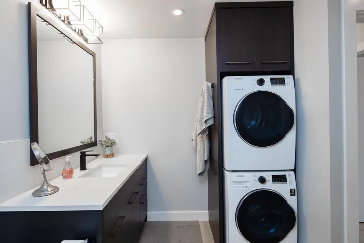 Laundry area with stacked washer / drying machine, a sink, baseboards, cabinet space, and recessed lighting
