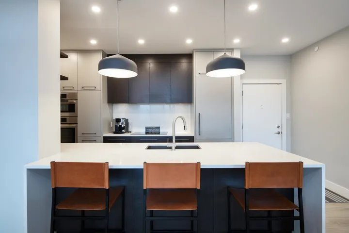 Kitchen with modern cabinets, a kitchen breakfast bar, double oven, light countertops, and a sink