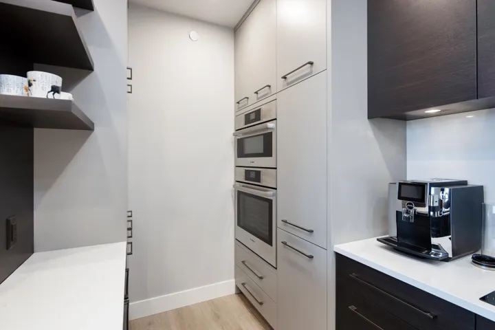Kitchen featuring modern cabinets, double oven, light countertops, and light wood-style flooring