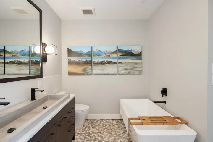 Bathroom featuring visible vents, baseboards, toilet, vanity, and a freestanding bath. Ensuite