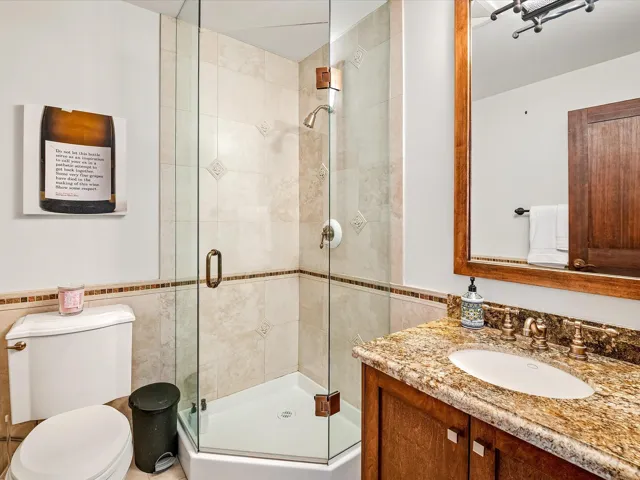 Full bathroom with tile walls, vanity, toilet, and a shower stall
