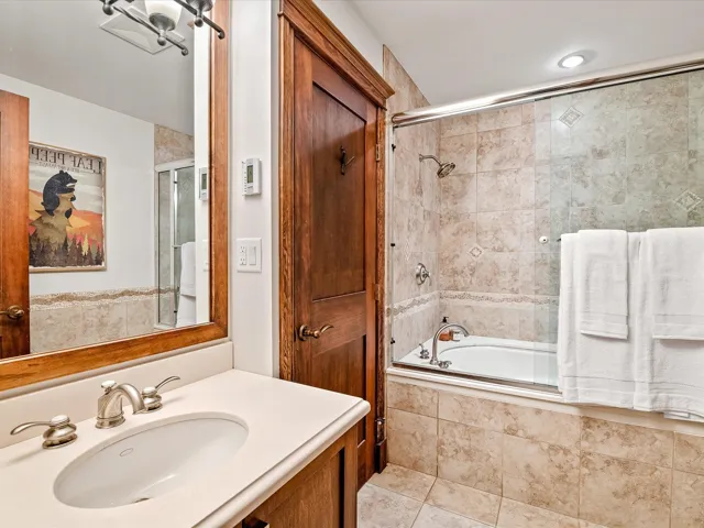 Bathroom with tiled shower / bath combo, tile patterned floors, and vanity