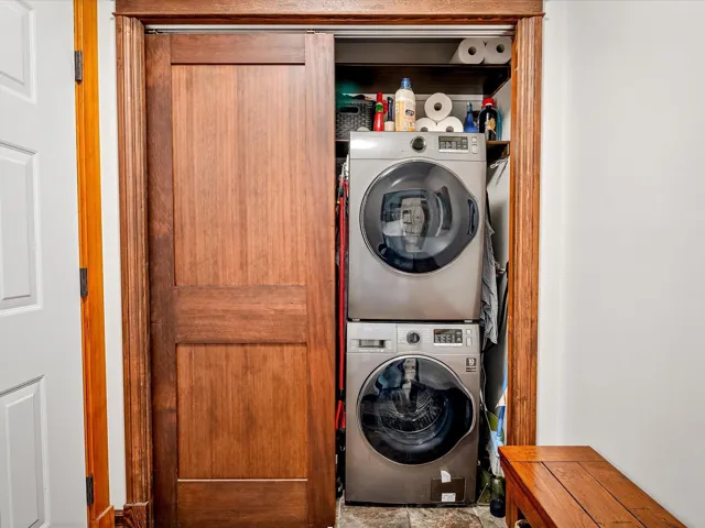 Washroom with stacked washer and clothes dryer and laundry area
