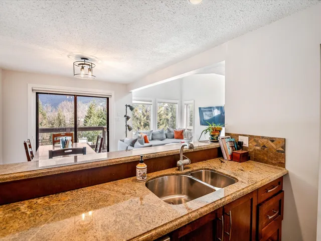 Kitchen with open floor plan, a sink, light stone counters, and a textured ceiling