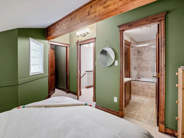 Unfurnished bedroom with a closet, lofted ceiling, tile patterned flooring, ensuite bathroom, and baseboards