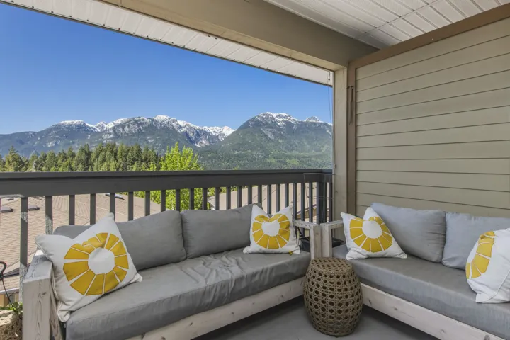 Covered balcony featuring a mountain and tree-lined horizon