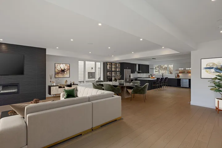 Living room featuring light wood-type flooring, beverage cooler, recessed lighting, a fireplace, and a raised ceiling