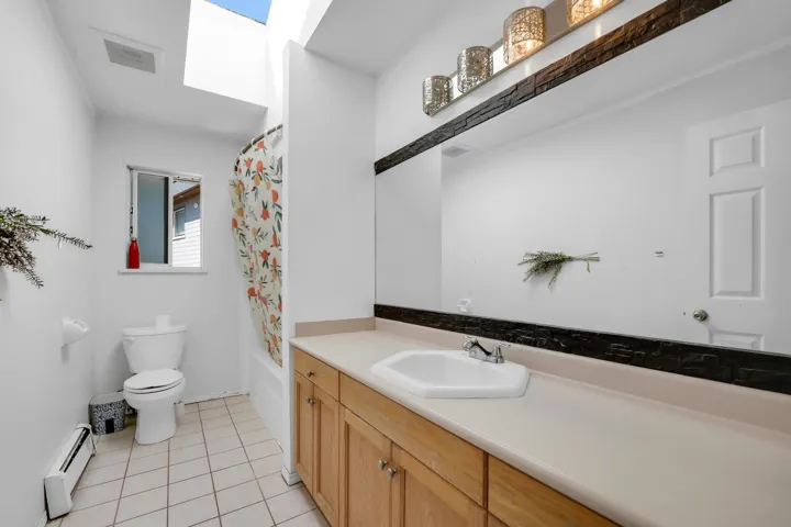 Bathroom with tile patterned flooring, visible vents, toilet, vanity, and a baseboard radiator