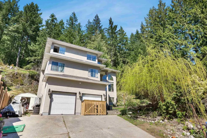 View of front of house with a garage, driveway, a storage unit, and stucco siding