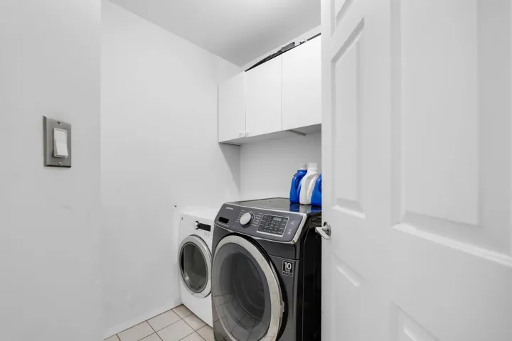 Clothes washing area with cabinet space, light tile patterned floors, and separate washer and dryer