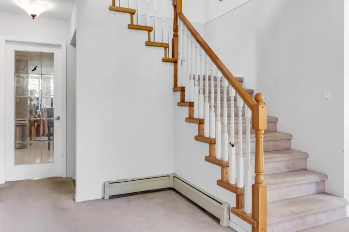 Stairway featuring a baseboard heating unit and carpet