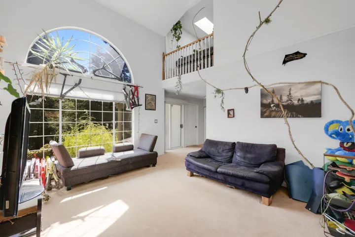 Living area with plenty of natural light, carpet flooring, and high vaulted ceiling