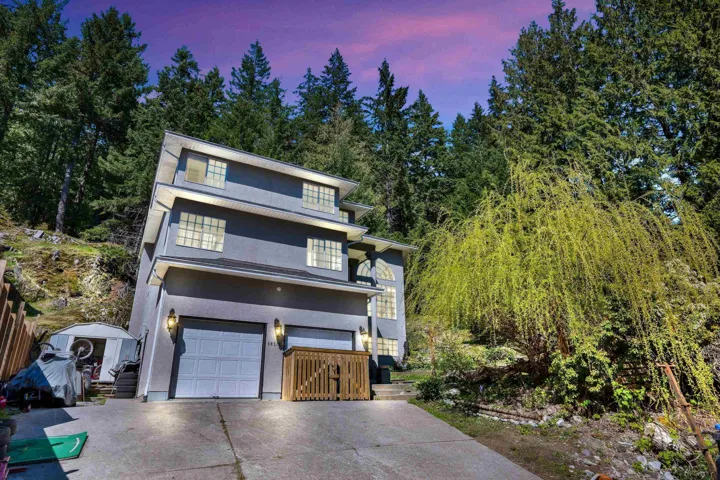 View of front of house with a storage shed, driveway, an attached garage, an outdoor structure, and stucco siding