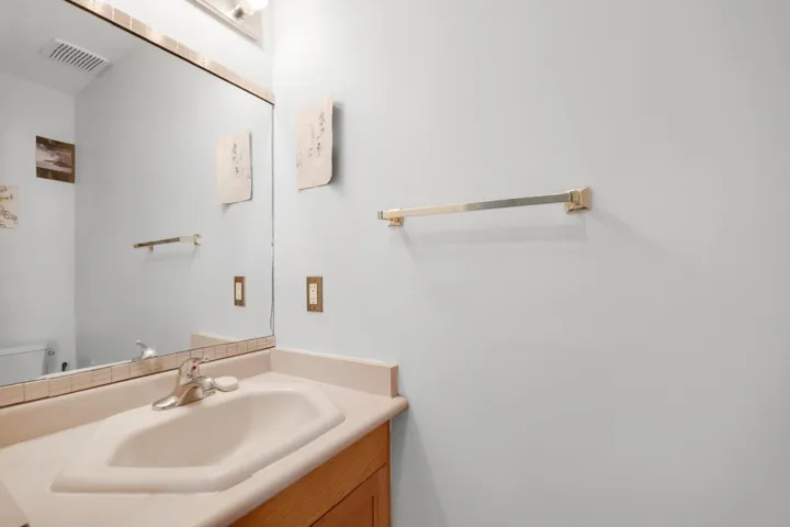 Half bath with toilet, vanity, and visible vents