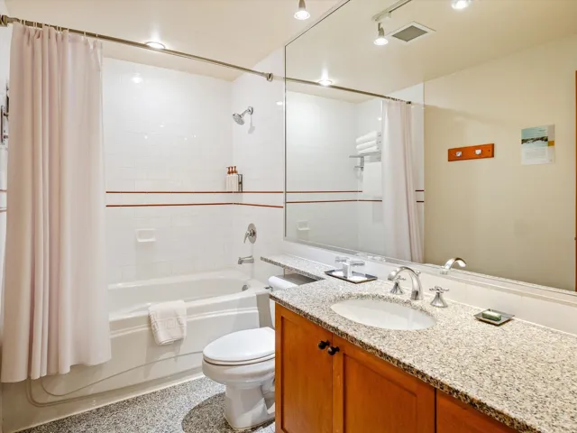 Full bathroom with visible vents, toilet, shower / bath combo with shower curtain, and vanity