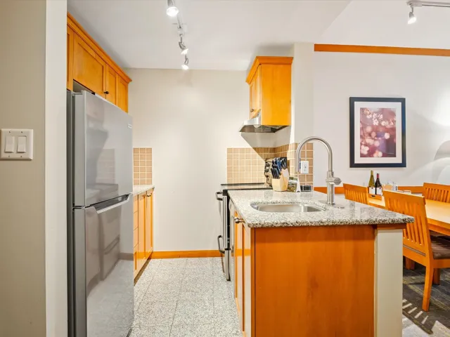 Kitchen featuring a sink, granite finish floor, stainless steel appliances, baseboards, and light stone countertops