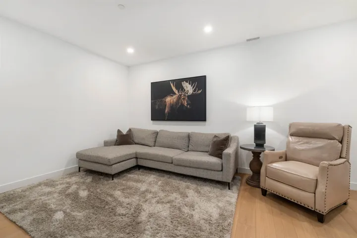 Recessed ceiling lighting illuminates the space, featuring light wood-finish flooring and crisp white walls