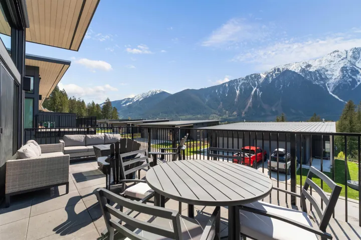Expansive outdoor patio with durable tile flooring and black metal railings, overlooking a prominent mountain range