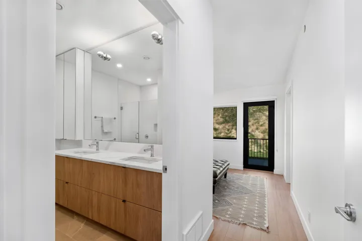 Dual vanity with stone countertop and integrated sinks, wood-finish cabinetry, and recessed lighting