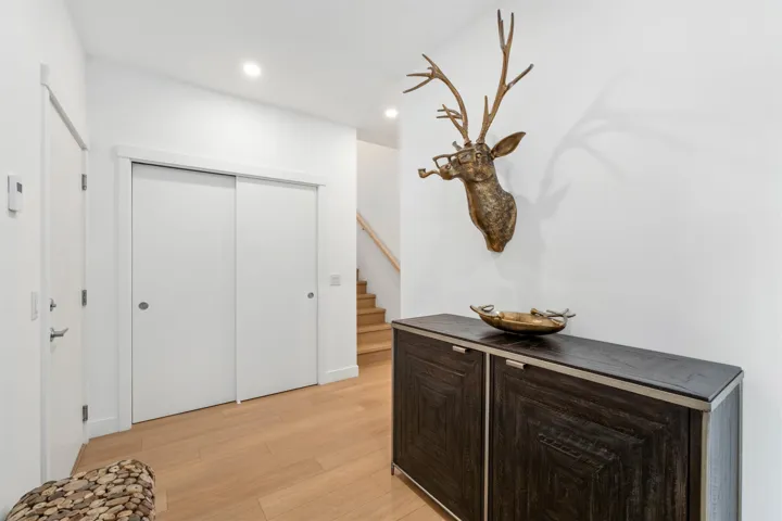 Hardwood-finish flooring, recessed lighting, white walls, and a built-in storage cabinet