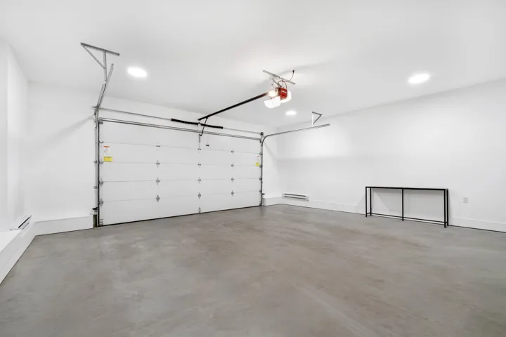 Concrete flooring, white walls, recessed ceiling lighting, garage door, baseboard heating