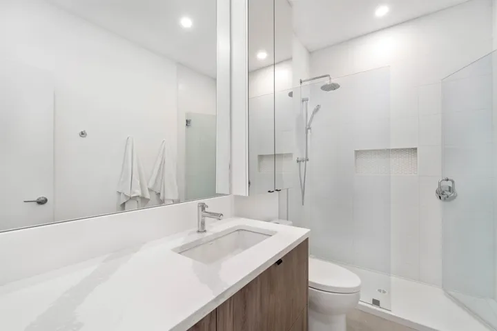 Integrated vanity with a single basin, wood-finish cabinetry, and a large wall-mounted mirror