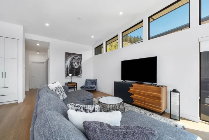 High ceilings with clerestory windows, wood-finish flooring, built-in cabinetry, recessed lighting, and a modern media console