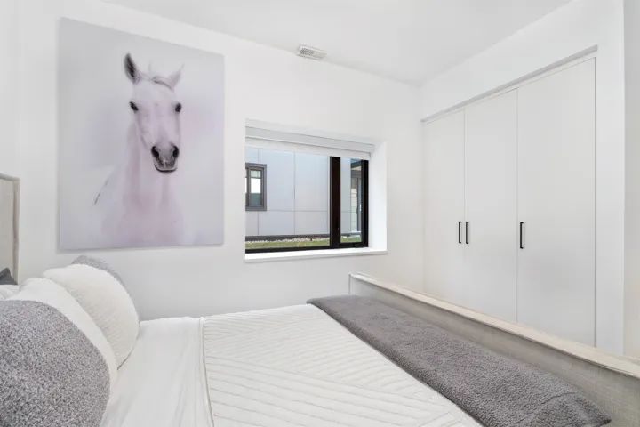 Built-in white cabinetry with black hardware, bright white walls, and a large window