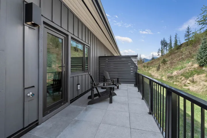 Exterior deck with a tile surface, a privacy screen, and a black metal railing