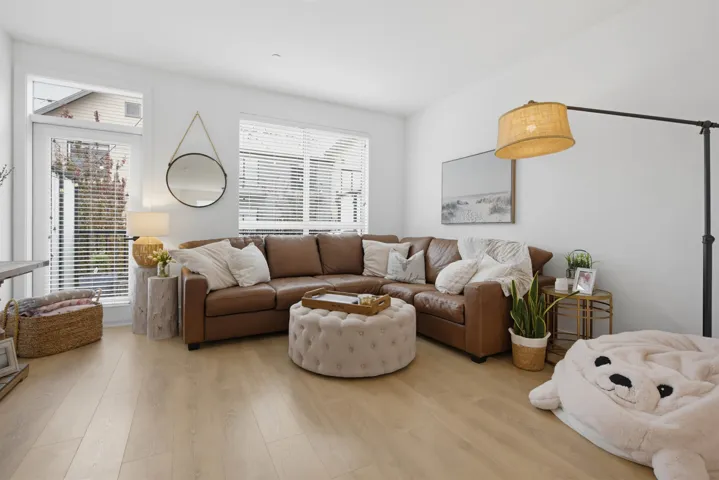 Open-concept living area with light wood-finish flooring, white walls, and recessed lighting