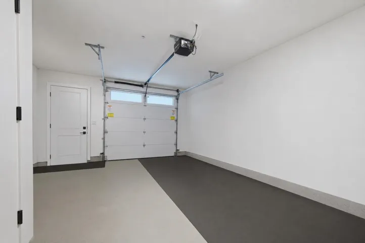 Spacious garage featuring a two-tone epoxy floor coating, automatic garage door opener, and a panel-style interior door