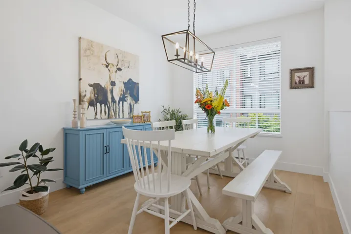 Open-concept kitchen featuring light wood-finish flooring, white cabinetry, a built-in stainless steel refrigerator, and a tile backsplash