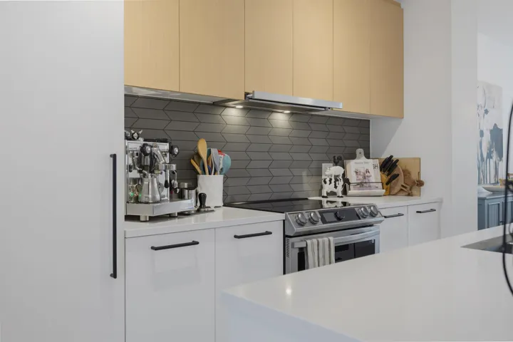 Contemporary kitchen with stainless steel appliances, light wood-finish flooring, and white cabinetry