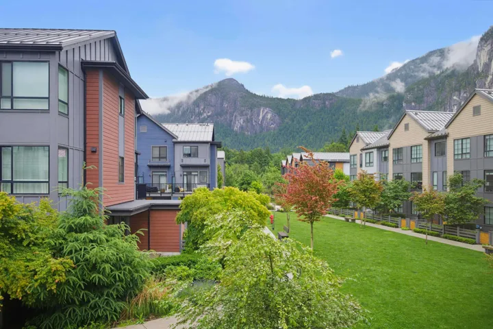 Modern townhome community featuring varied exterior siding, pitched metal roofs, and large windows