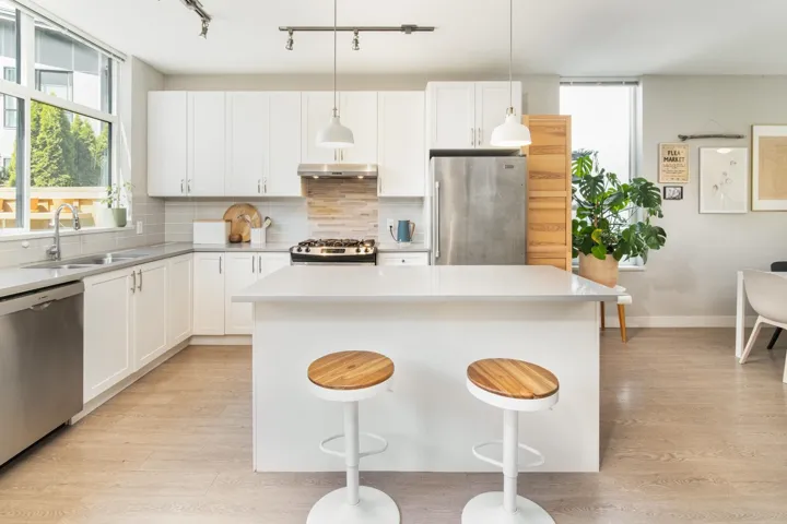 Kitchen with appliances with stainless steel finishes, under cabinet range hood, a sink, and backsplash