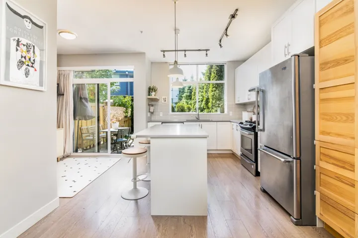 Kitchen featuring stainless steel appliances, healthy amount of natural light, backsplash, and light wood-style flooring