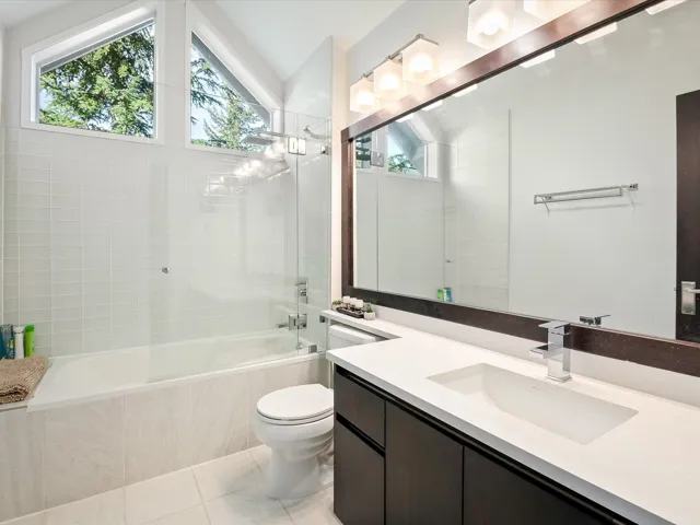 Full bathroom featuring tiled shower / bath combo, toilet, vaulted ceiling, vanity, and tile patterned flooring