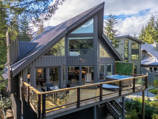 Back of property with a deck, board and batten siding, metal roof, and stairs
