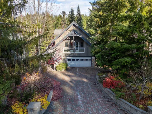 View of front facade with stone siding, decorative driveway, an attached garage, and board and batten siding