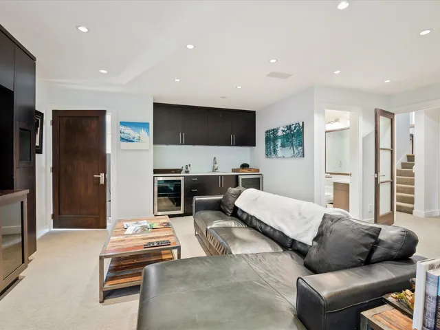 Living room featuring beverage cooler, recessed lighting, indoor wet bar, light carpet, and stairs